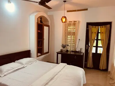 a bedroom with a bed and a dresser and a window at Mathangi - A Countryside Homestay for Family and Solo Travelers in Kozhikode