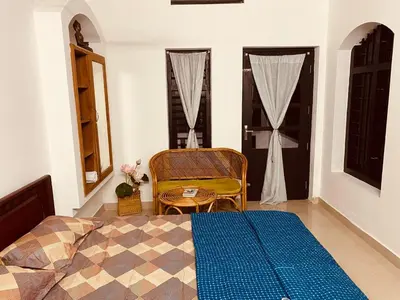 a bedroom with a bed and a chair and a window at Mathangi - A Countryside Homestay for Family and Solo Travelers in Kozhikode