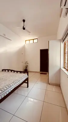 an empty room with a bed and a window at Snehanilayam-1 in Trichūr