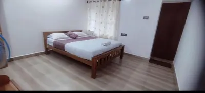 a bedroom with a bed with white sheets and pillows at Blue chill villa in Madikeri