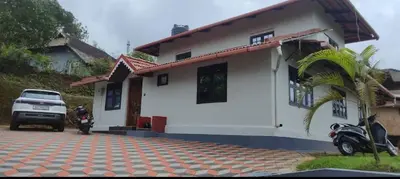 a house with a motorcycle parked in front of it at Blue chill villa in Madikeri