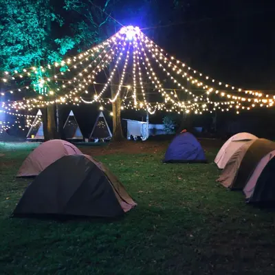 a group of tents in a field with lights at Green mountain resort in Meppādi
