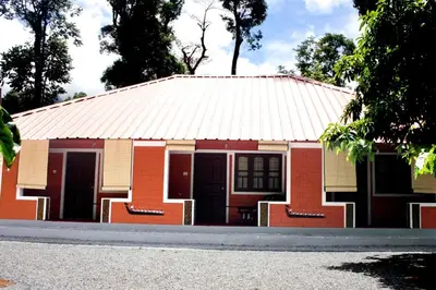 a red house with a tin roof on a street at Green mountain resort in Meppādi