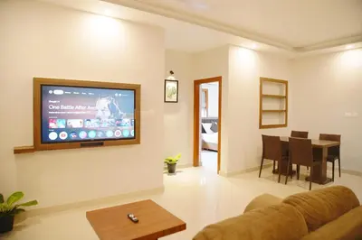 a living room with a couch and a tv on the wall at Blue Vista Residency in Kalpetta