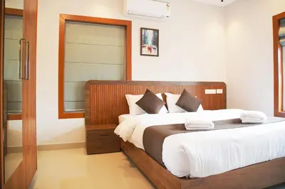 a bedroom with a large bed with white sheets at Blue Vista Residency in Kalpetta