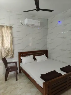 a bedroom with a bed and a chair in it at Eshwaraa Cottage in Palani