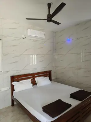 a bedroom with a bed with a ceiling fan at Eshwaraa Cottage in Palani