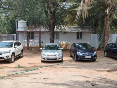 three cars parked in a parking lot in front of a house at Eshwaraa Cottage in Palani
