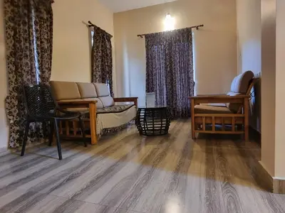 a living room with a couch and a chair at Honey Bee Cottages in Ooty