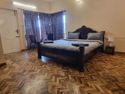 a bedroom with a bed with a wooden floor at Honey Bee Cottages in Ooty