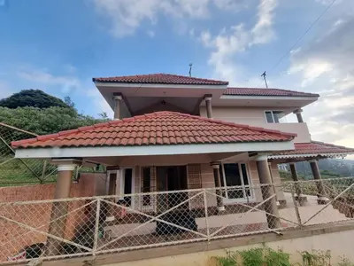 a house with a red roof and a fence at Honey Bee Cottages in Ooty