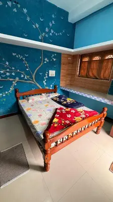 a wooden bed in a room with a blue wall at Adi Home Stay in Vālpārai