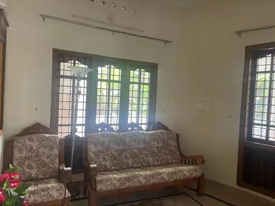 a living room with a couch and two windows at Authentic Keralite holiday home for up to 6 in Kāladi