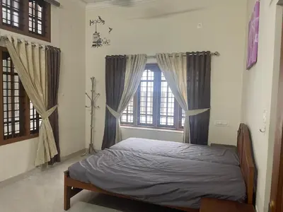 a bedroom with a bed in a room with windows at Authentic Keralite holiday home for up to 6 in Kāladi