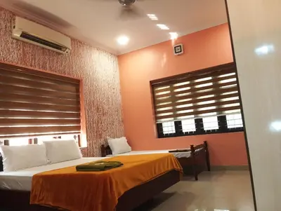 a bedroom with orange walls and a bed and a window at Gayathri in Trichūr