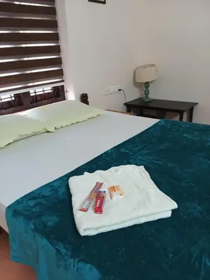 a bed with a towel and a pair of scissors on it at Gayathri in Trichūr
