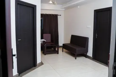 a living room with a black chair and a chair at krishna suites guruvayur in Guruvāyūr