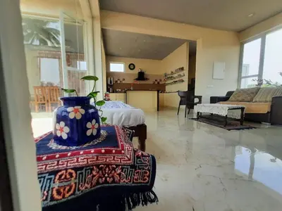 a large living room with a vase on a table at Glass house in Pollāchi