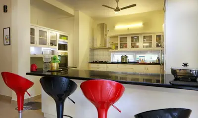 a kitchen with red stools in front of a counter at Family beach home-Cherai in Pallipuram