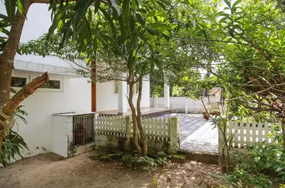 a house with a tree in front of a fence at Family beach home-Cherai in Pallipuram