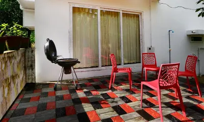 a group of red chairs and a grill on a porch at Family beach home-Cherai in Pallipuram