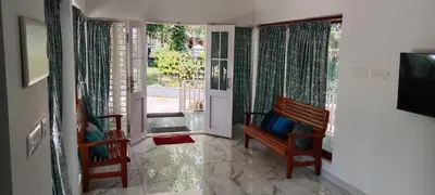 a living room with two chairs and a sliding glass door at Bougainvilla Luxury Individual Villa Kozhikode in Kunnamangalam