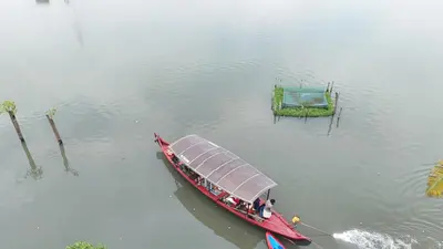 a red boat with a cover in the water at Atharvam Resort in Cherai Beach