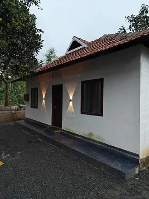 a white house with lights on the side of it at Hayden in Kakkadampoyil