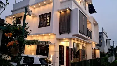 a white house with a car parked in front of it at Mendez Residency in Ernakulam