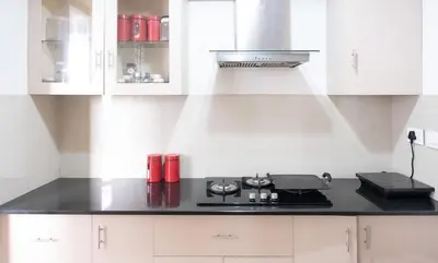a kitchen with white cabinets and a stove top oven at 2BHK with Pool and Rooftop at the Centre of Kozhikode in Kozhikode