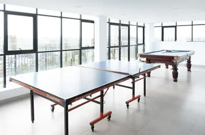 two ping pong tables in a large room with windows at 2BHK with Pool and Rooftop at the Centre of Kozhikode in Kozhikode