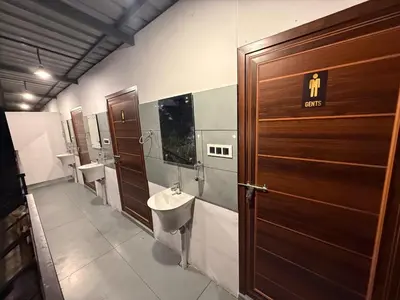 a bathroom with two sinks and two toilets and a wooden door at Boche LuxCamp 1000 Acre in Wayanad