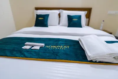 a bed with a blue blanket and towels on it at Hotel Aeronest Residency in Calicut
