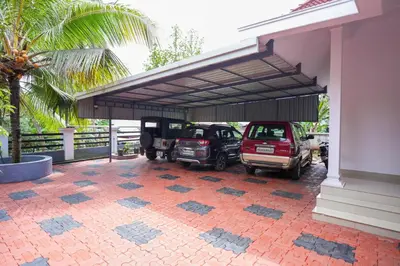 a parking lot with two cars parked under a garage at Guruvayur Nature Homestay in Kunnamkulam