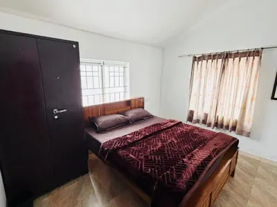 a bedroom with a bed and a large window at Majestry Cottage in Ooty