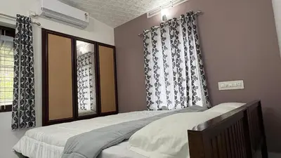 a bedroom with a bed and a window with curtains at Ravi's homestay in Cochin