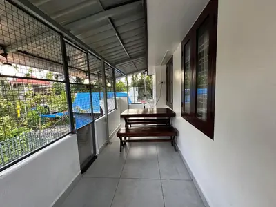 a room with a table and a bench and windows at Ravi's homestay in Cochin