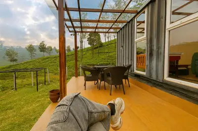 a person laying on the porch of a house at The Leafy Nook Container Stay- 360 degree Tea Plantation near Ooty in Coonoor