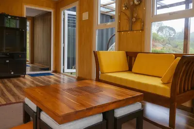 a living room with a yellow couch and a table at The Leafy Nook Container Stay- 360 degree Tea Plantation near Ooty in Coonoor