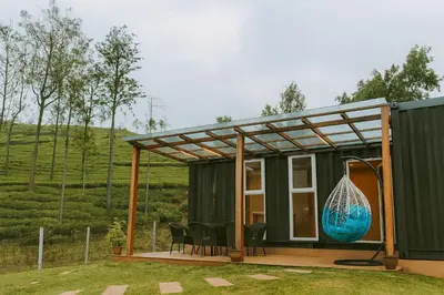 a green house with a large blue vase on a deck at The Leafy Nook Container Stay- 360 degree Tea Plantation near Ooty in Coonoor