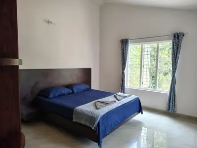 a bedroom with a bed with blue sheets and a window at Sintra Villa in Meppādi