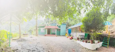a small house in the middle of a yard at Greenwoods Mist Villa in Munnar