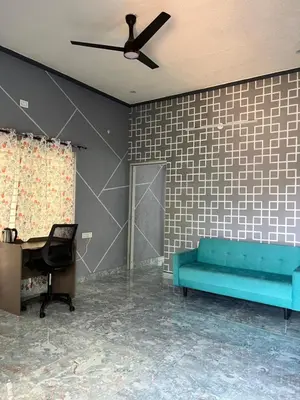 a living room with a blue couch and a ceiling fan at Chamundi Temple-Hill View in Mysore