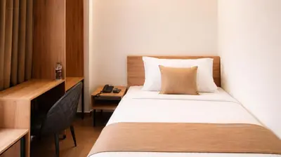 a small bedroom with a bed and a desk at Nexstay Bayyat Inn in Kozhikode