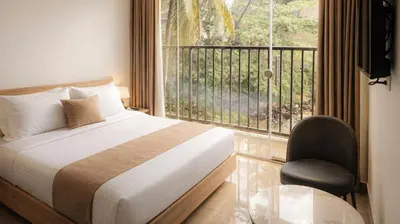 a bedroom with a bed and a balcony with a chair at Nexstay Bayyat Inn in Kozhikode