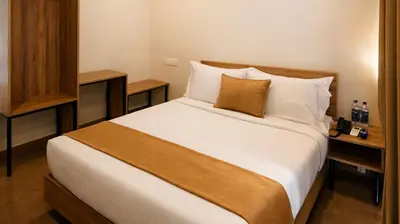 a bedroom with a large bed with white sheets at Nexstay Bayyat Inn in Kozhikode