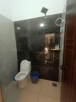 a bathroom with a toilet and a black wall at Serene riverside retreat in Kozhikode