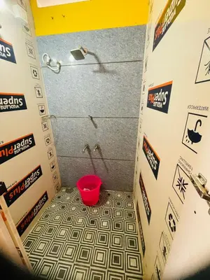 a bathroom with a shower with a red bucket at Avenue Dorms in Kalpetta
