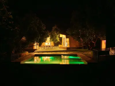 a pool with green lights in a yard at night at Bougain Villa Hilltreat in Muthalamada