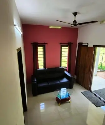 a living room with a black leather couch and red wall at Forest edge Villa - 3 bedrooms in Ambalavayal
